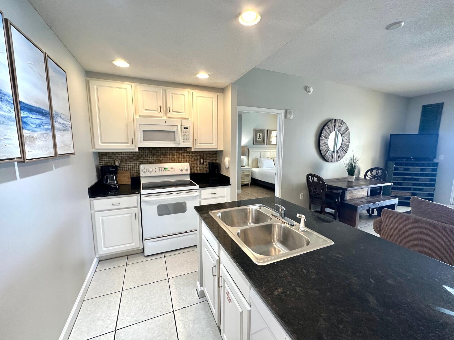12011 Front Beach Road, Unit 103B Panama City Beach, FL 32407 - Photo 7 of 38 a kitchen with a stove a sink and a refrigerator
