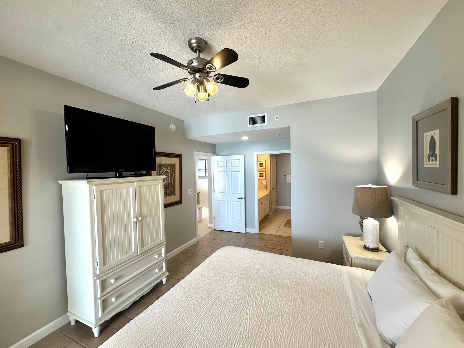 12011 Front Beach Road, Unit 103B Panama City Beach, FL 32407 - Photo 9 of 38 a bedroom with a bed and a flat screen tv