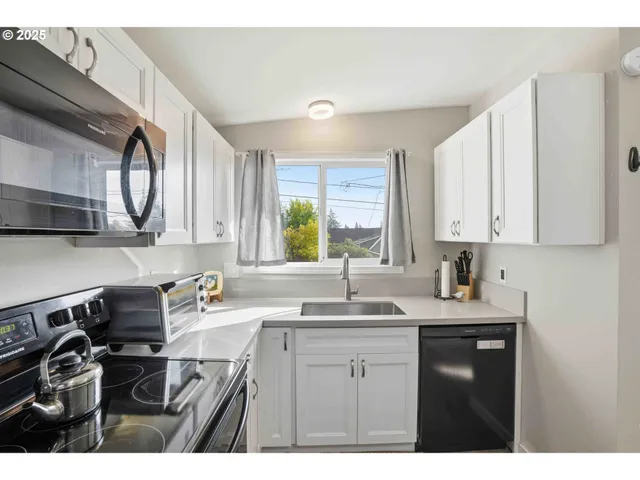 a kitchen with a sink a stove cabinets and a window