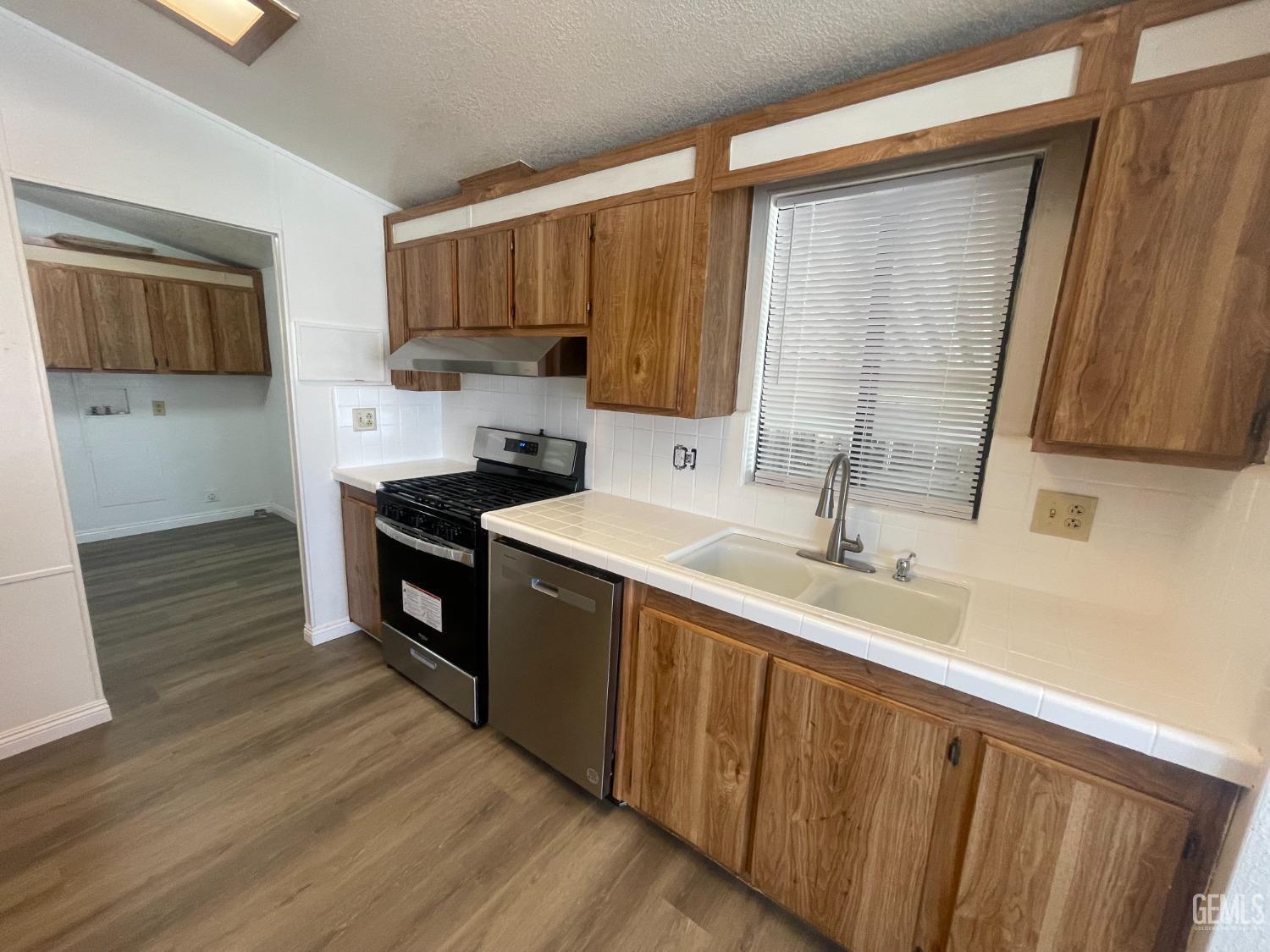 Undisclosed Address Bakersfield, CA 93307 - Photo 2 of 18 a kitchen with stainless steel appliances a sink cabinets and wooden floor