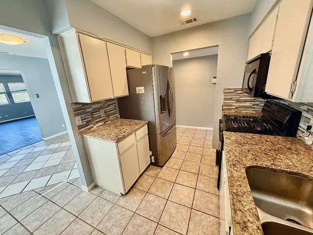 a kitchen with granite countertop a stove a refrigerator and cabinets