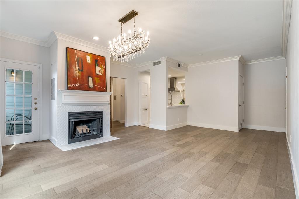 4034 Rawlins Street, Unit 104 Dallas, TX 75219 - Photo 5 of 19 a view of a livingroom with a fireplace a chandelier and windows