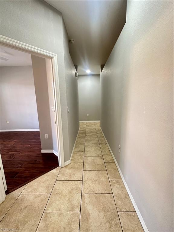 7350 Bristol Circle Naples, FL 34120 - Photo 14 of 14 Corridor with light tile patterned floors and a textured wall