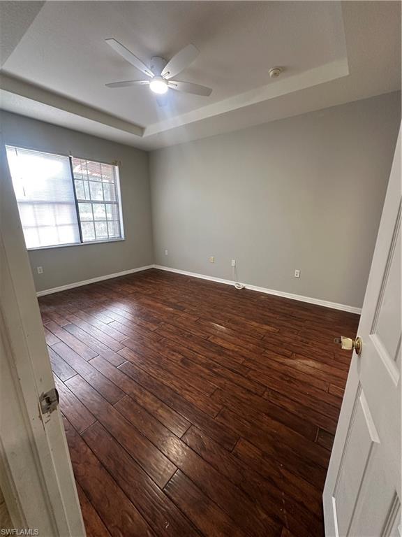 7350 Bristol Circle Naples, FL 34120 - Photo 10 of 14 Empty room with a raised ceiling, dark wood-type flooring, and a ceiling fan