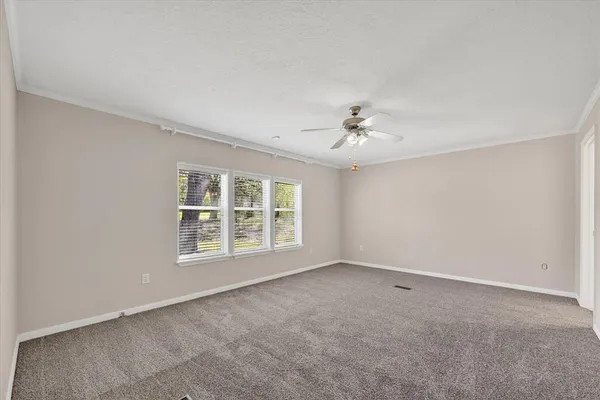 an empty room with a chandelier fan and windows