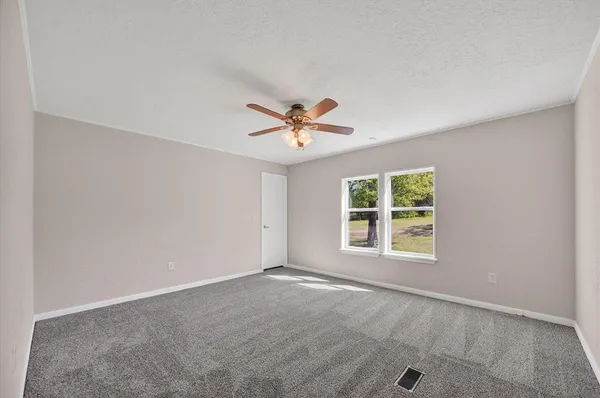 an empty room with a ceiling fan and window
