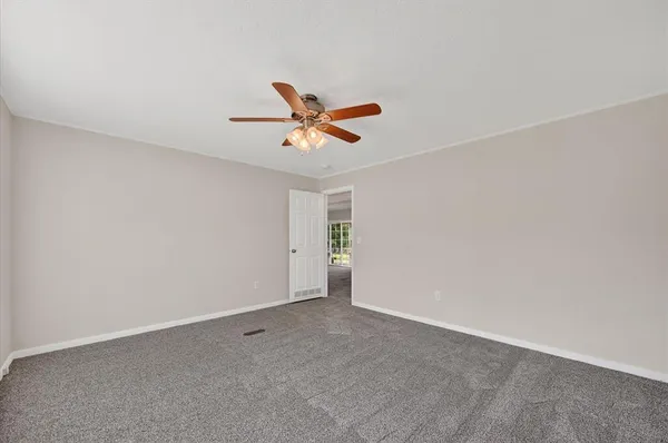 an empty room with closet and a ceiling fan