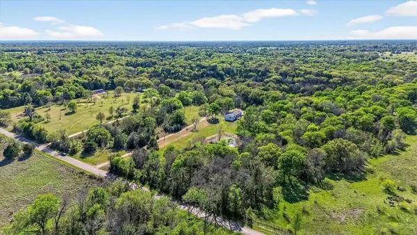 an aerial view of residential houses with outdoor space and trees