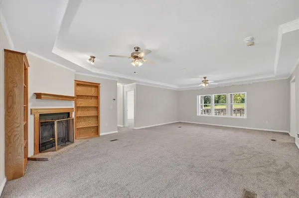 a view of an empty room with a window and fireplace