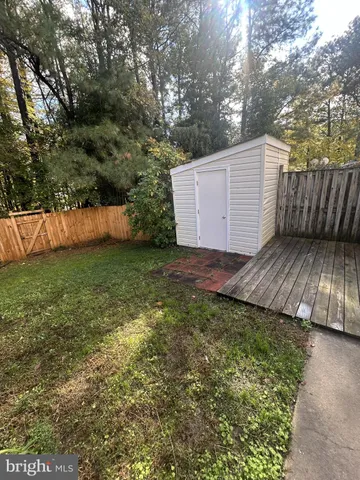 a view of backyard with wooden fence and large trees