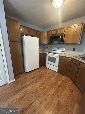 a kitchen with a refrigerator sink and wooden cabinets