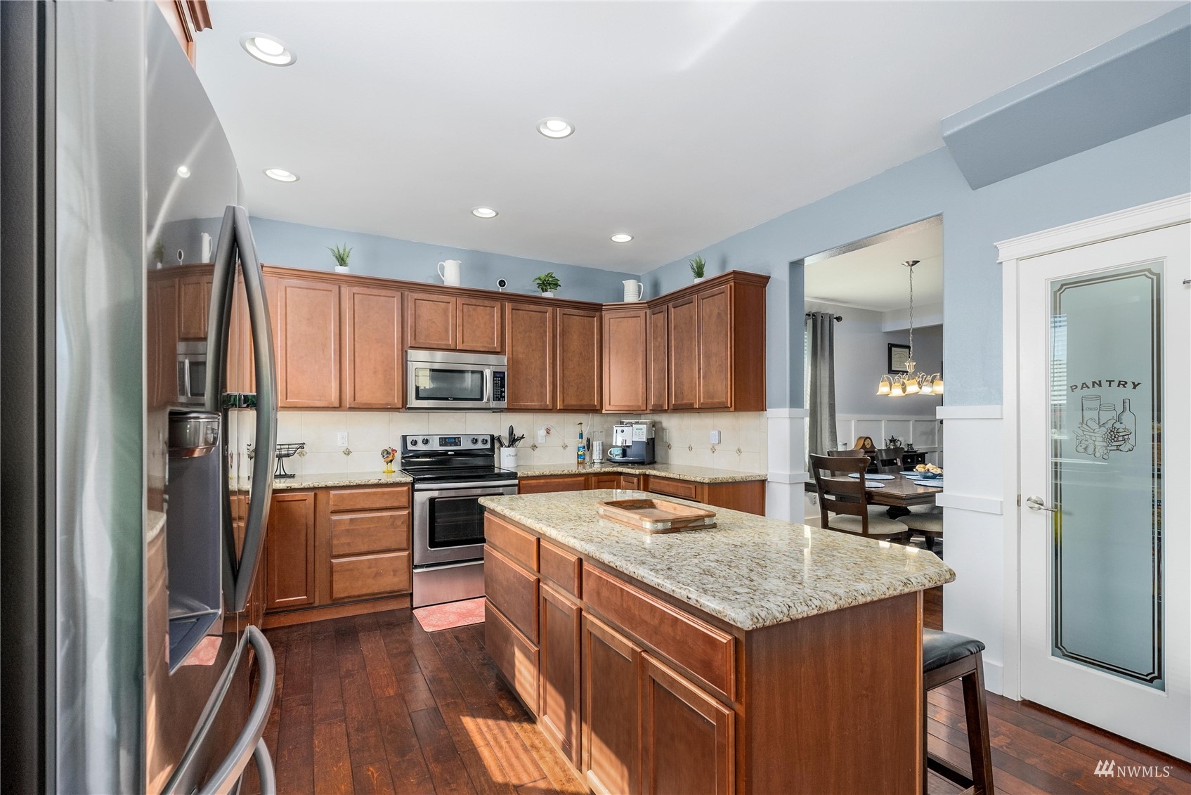 1333 Farina Loop Southeast Olympia, WA 98513 - Photo 6 of 32 a kitchen with stainless steel appliances granite countertop a stove top oven a refrigerator a sink and dishwasher with wooden floor