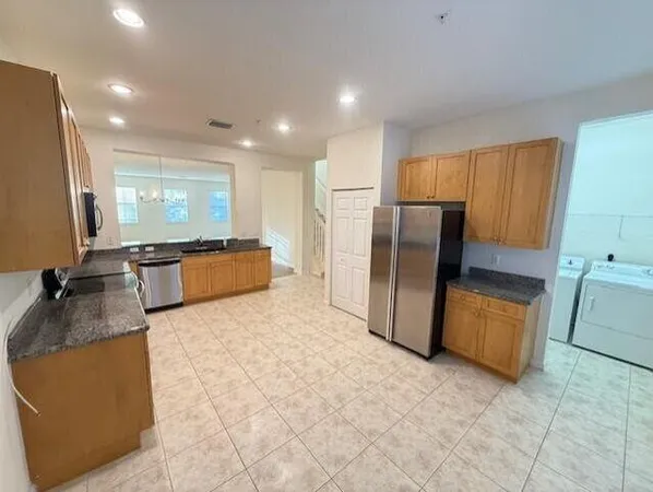 a large kitchen with stainless steel appliances granite countertop a refrigerator and a stove