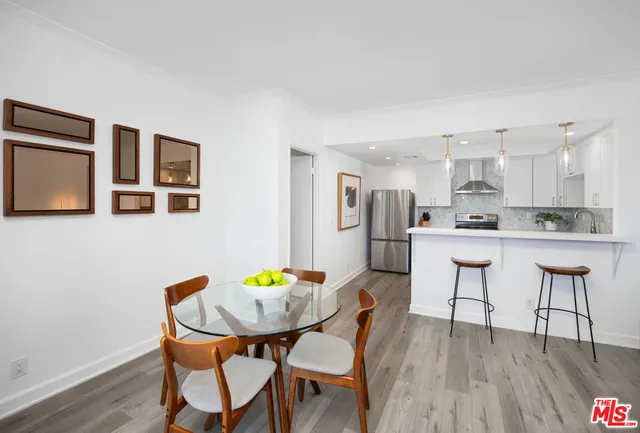 a kitchen with stainless steel appliances kitchen island granite countertop a dining table chairs and a refrigerator