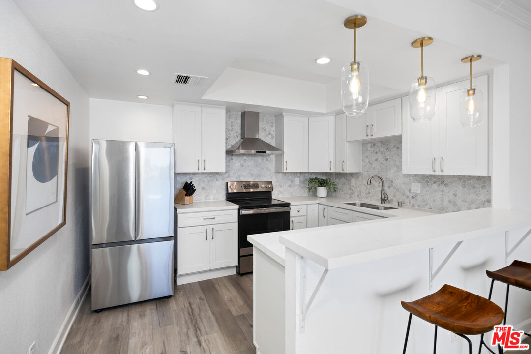 321 South San Vicente Boulevard, Unit 708 Los Angeles, CA 90048 - Photo 5 of 19 a kitchen with a refrigerator a stove and white cabinets with wooden floor