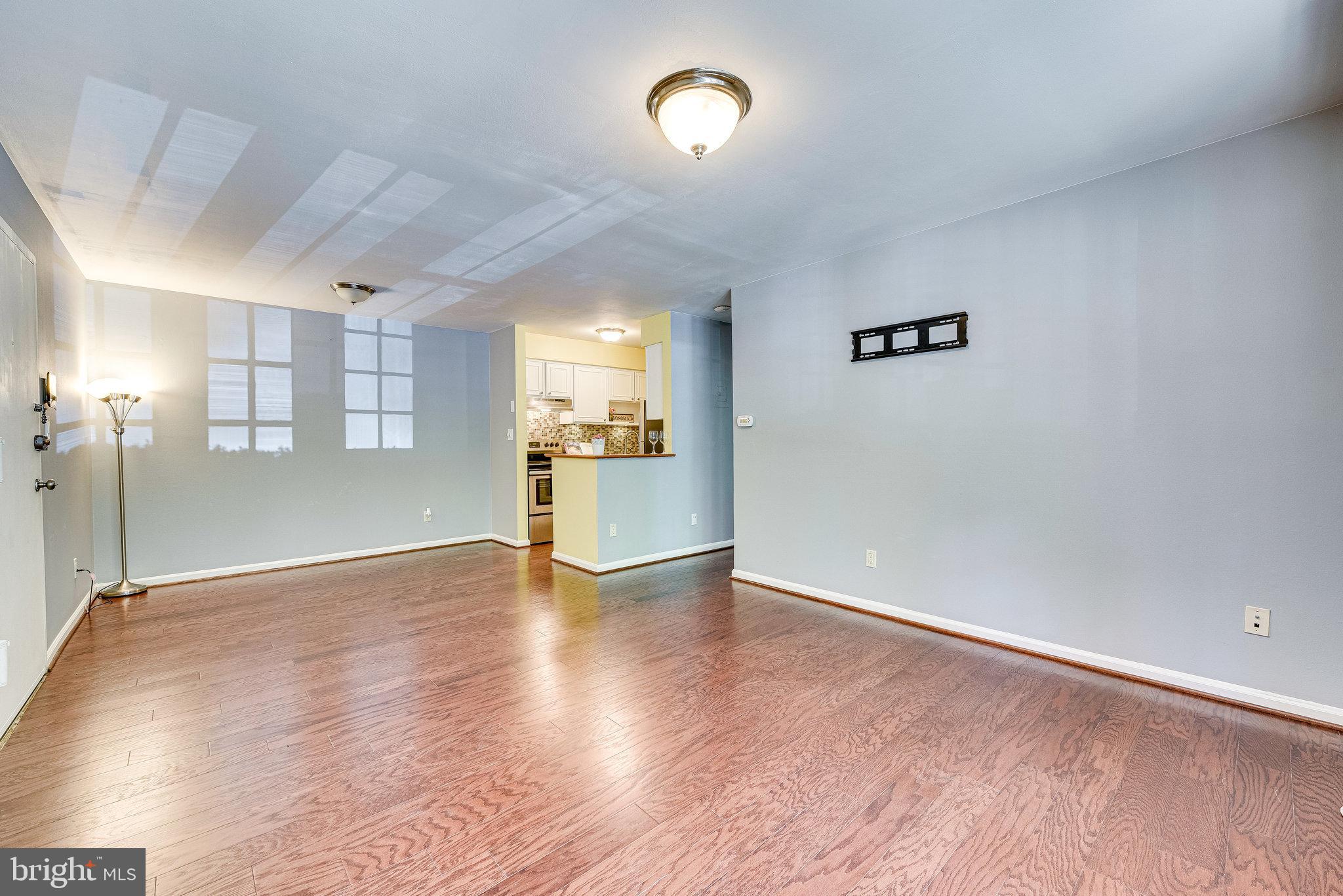5909 B Prince James Drive, Unit B Springfield, VA 22152 - Photo 17 of 18 an empty room with wooden floor and a kitchen
