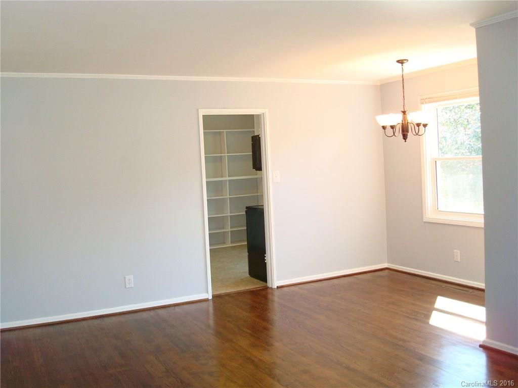 744 Manhasset Road Charlotte, NC 28209 - Photo 3 of 20 an empty room with wooden floor cabinet and windows