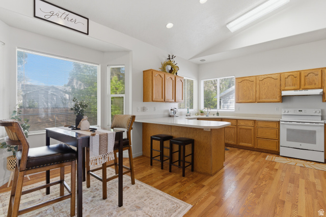 134 West 475 South Ogden, UT 84404 - Photo 6 of 27 Kitchen featuring vaulted ceiling, light countertops, electric range, a peninsula, and a kitchen bar