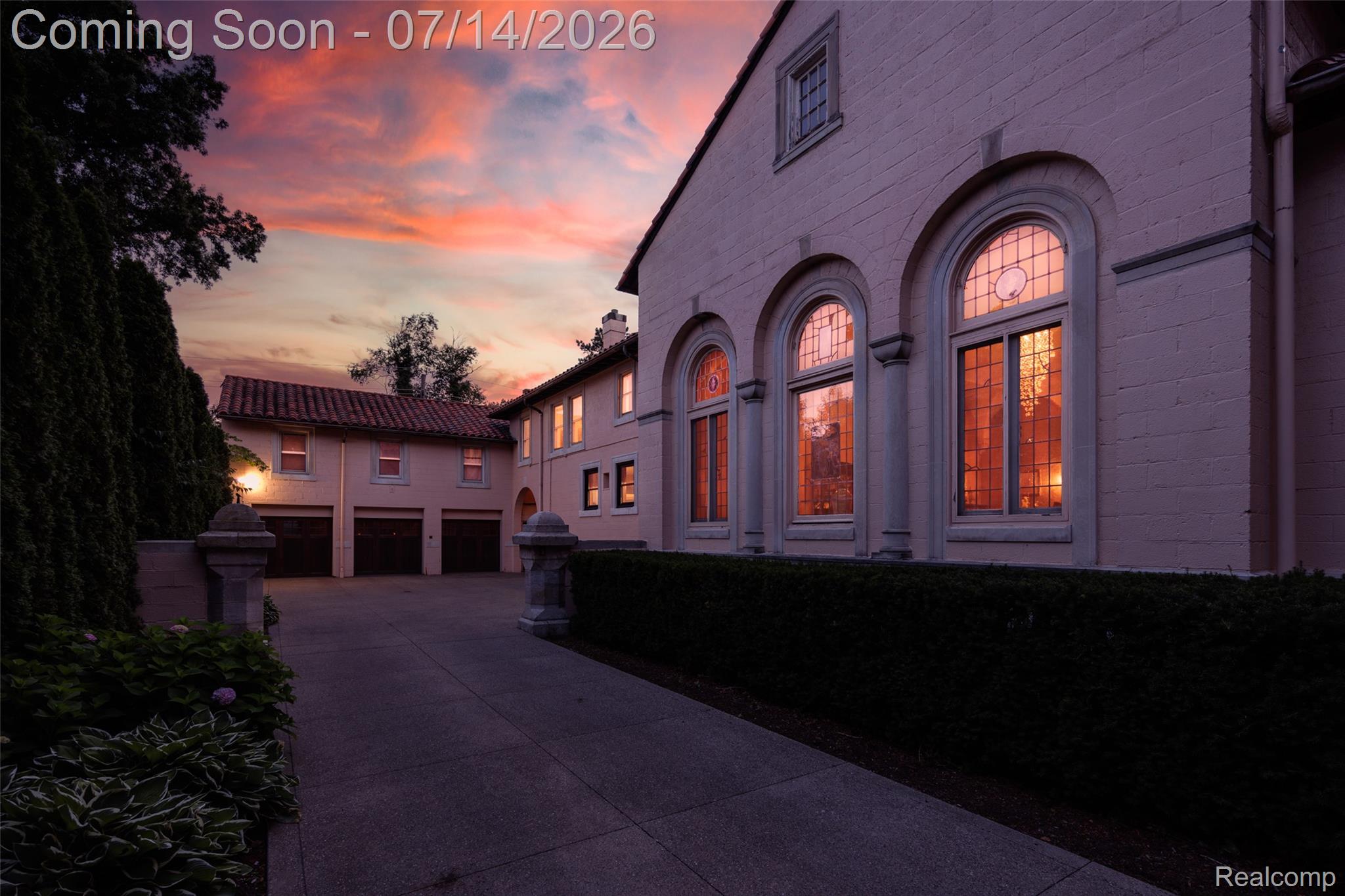 189 Cloverly Road Grosse Pointe, MI 48236 - Photo 92 of 96 Stucco exterior featuring arched windows with leaded glass accents, a multi-car garage with individual doors, and a concrete driveway