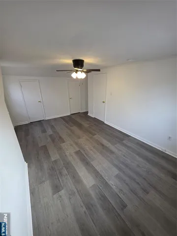 an empty room with wooden floor chandelier fan and view