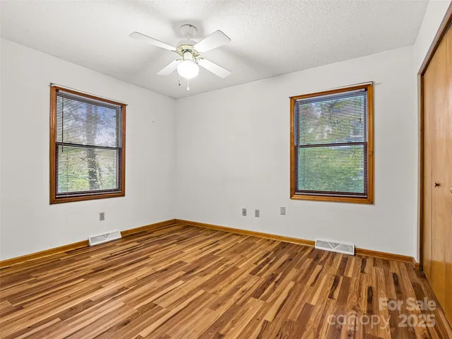 a view of an empty room with a window and wooden floor