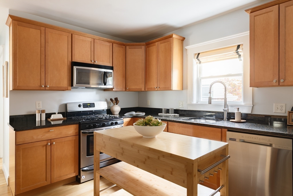 128 Thorndike Street, Unit 128 Arlington, MA 02474 - Photo 6 of 20 a kitchen with granite countertop a sink stove top oven and cabinets