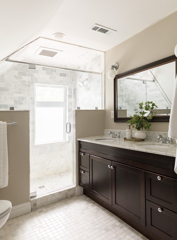 128 Thorndike Street, Unit 128 Arlington, MA 02474 - Photo 9 of 20 a bathroom with a double vanity sink toilet and a mirror