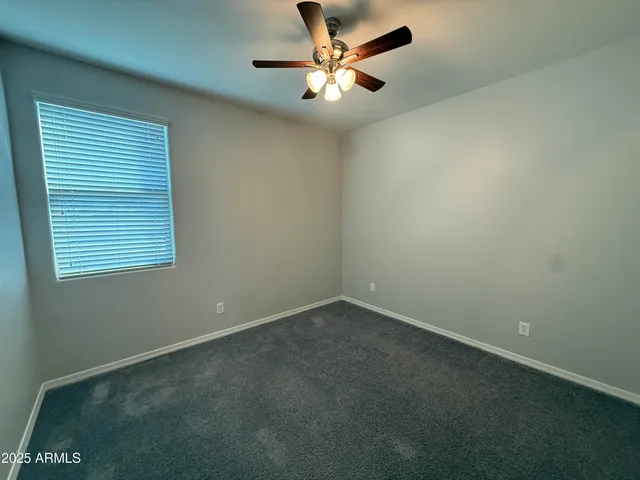 an empty room with closet and a ceiling fan