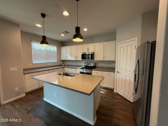 a kitchen that has a lot of cabinets a sink and wooden floor