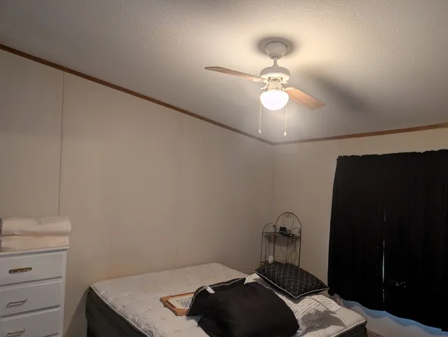 a bedroom with a bed and a chandelier fan