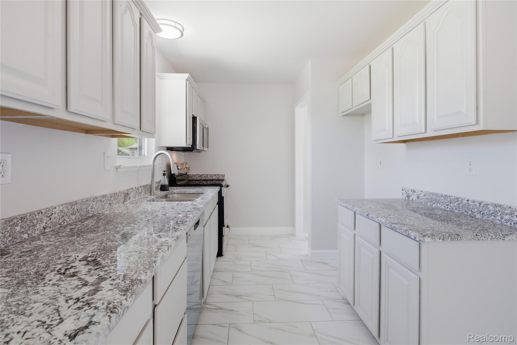 37257 Dundee Street Sterling Heights, MI 48310 - Photo 13 of 47 Kitchen featuring extensive white cabinetry, granite-style countertops, stainless steel sink with gooseneck faucet, built-in microwave, and wood-finish flooring