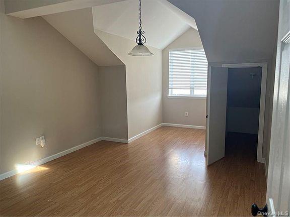 1418 Outlook Avenue, Unit 3 Bronx, NY 10465 - Photo 6 of 9 an empty room with wooden floor and windows