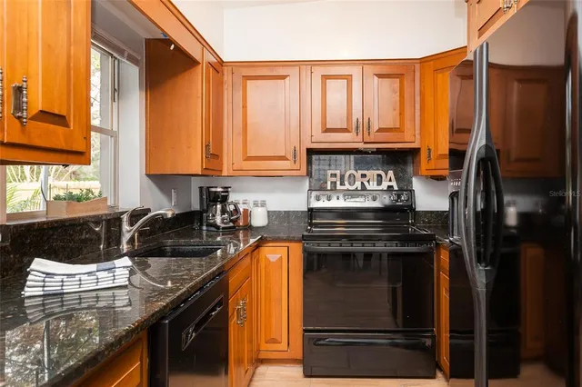 a kitchen with granite countertop a sink stove and refrigerator