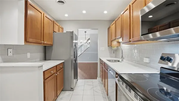 a kitchen that has a sink a stove and stainless steel appliances