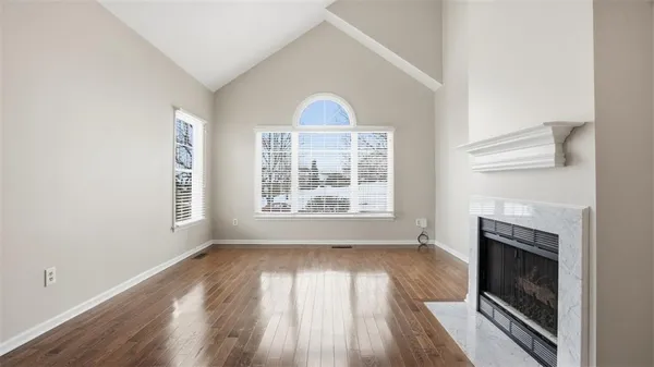 a view of an empty room with wooden floor fireplace and a window