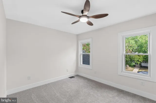an empty room with windows and ceiling fan
