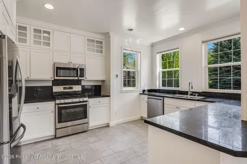 a kitchen with stainless steel appliances granite countertop a stove a sink and a microwave