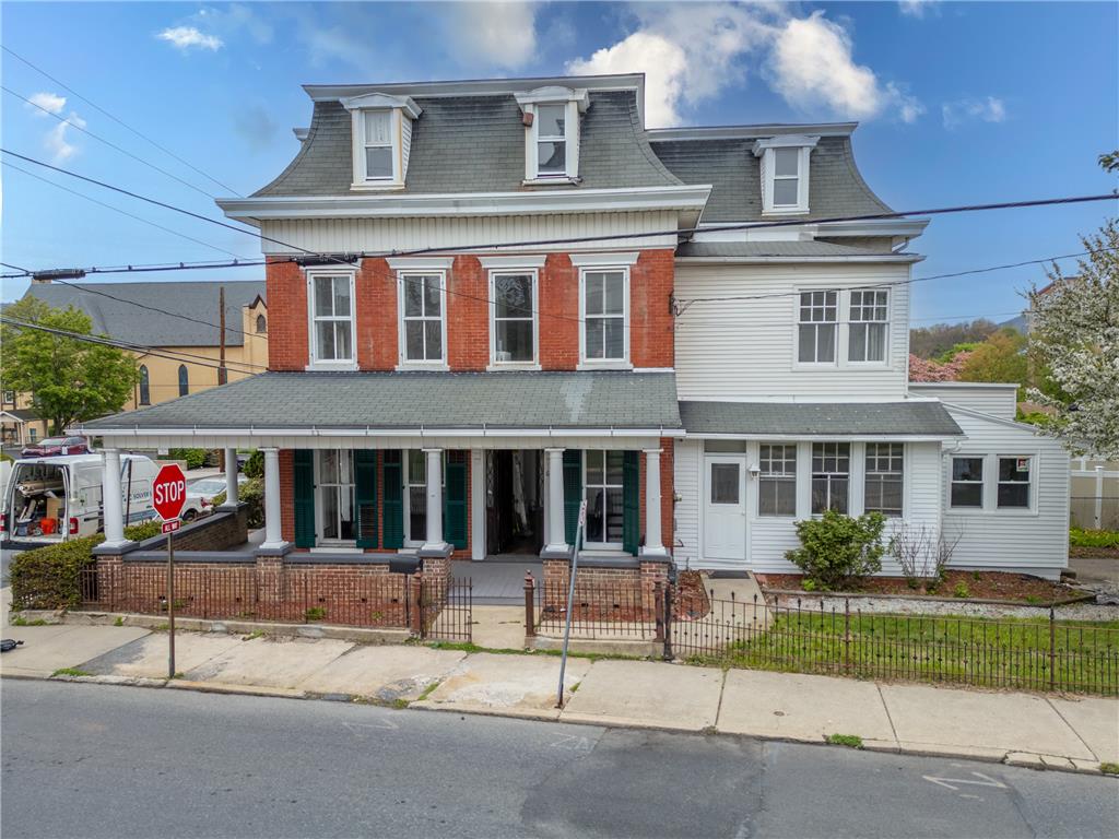 This classic facade combines brick and siding, featuring a charming covered porch with white columns.