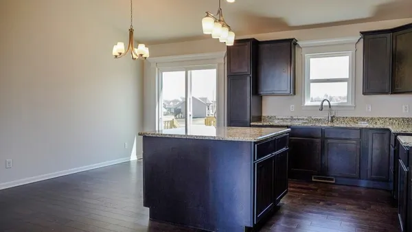 a kitchen with granite countertop a sink cabinets and wooden floor