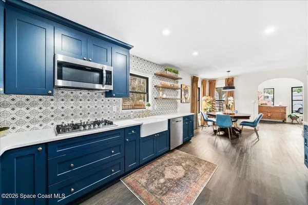 a large kitchen with stainless steel appliances granite countertop a lot of counter space and wooden floor