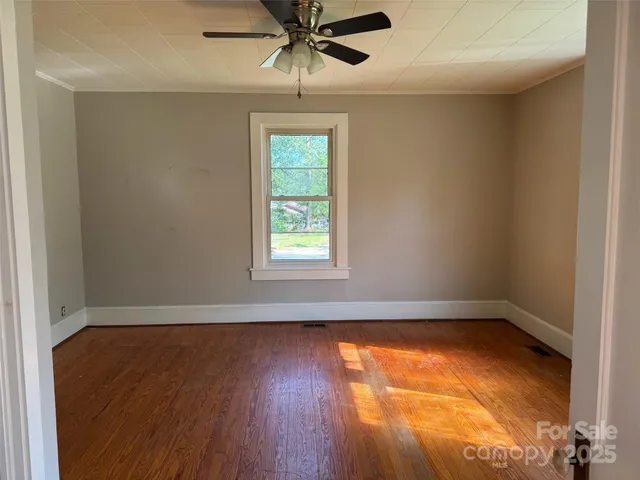 an empty room with a window and wooden floor