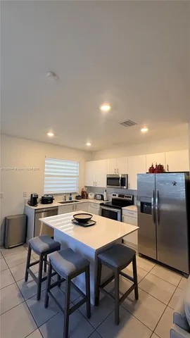 a kitchen with a dining table chairs and refrigerator