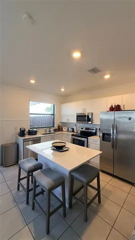 a kitchen with a dining table chairs and refrigerator