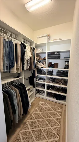 a view of walk in closet with clothes and shoes