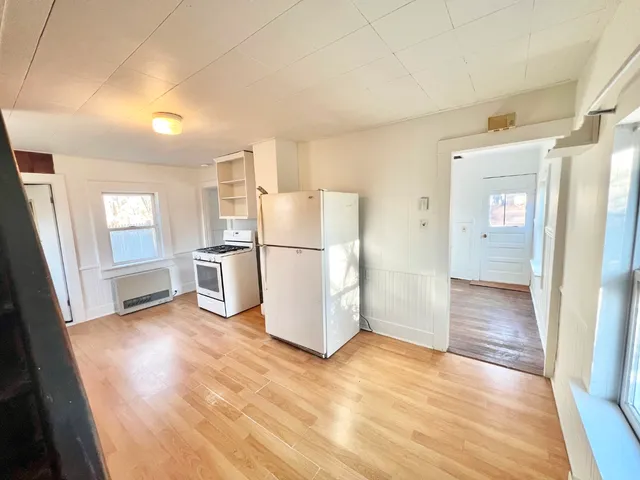 a view of a kitchen with refrigerator and wooden floor