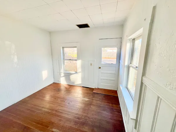 a view of an empty room with wooden floor and a window
