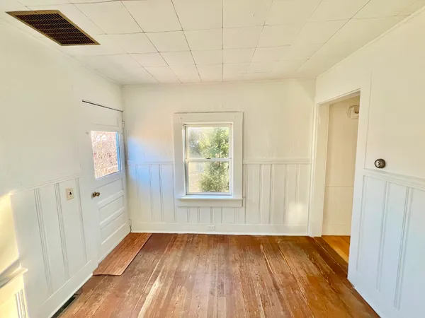 a view of an empty room with wooden floor and a window