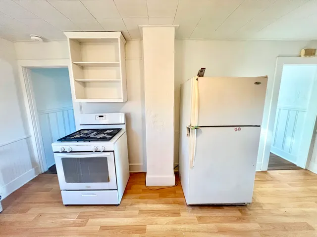 a view of a kitchen with wooden floor and a refrigerator