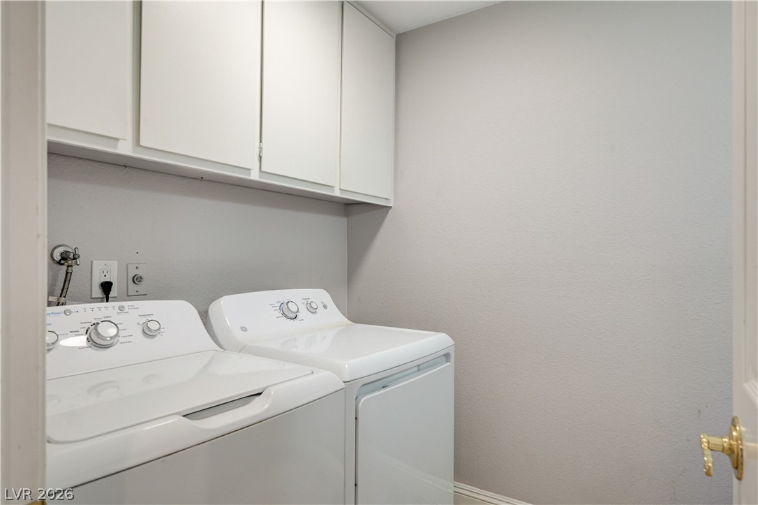 6635 Costa Brava Road Las Vegas, NV 89146 - Photo 23 of 59 Functional laundry room equipped with upper cabinetry and a washer/dryer set.