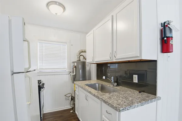 a kitchen with a granite countertop sink and cabinets